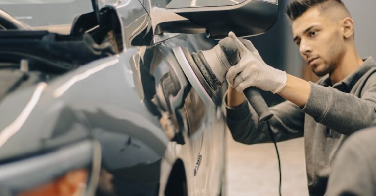A focused worker polishes a vehicle with precision, enhancing its shine indoors.
