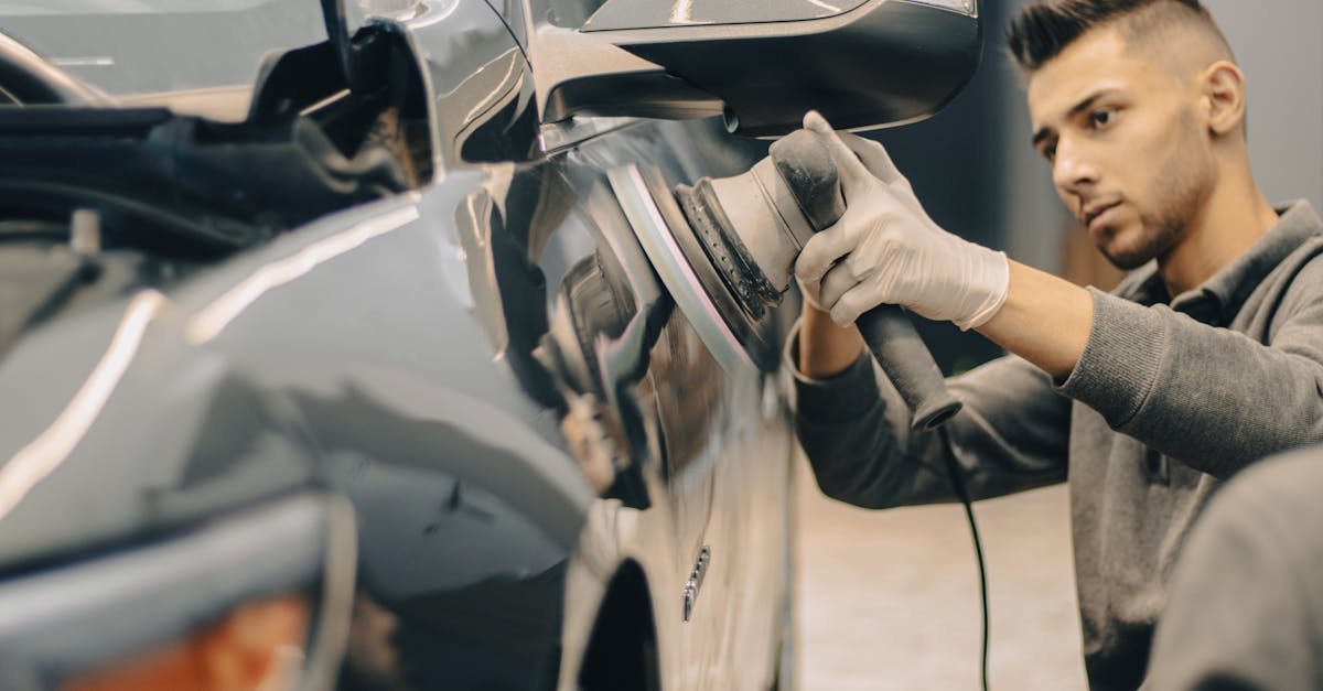 A focused worker polishes a vehicle with precision, enhancing its shine indoors.