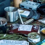 A diverse assortment of camping and survival items laid out, including food, tools, and gadgets.