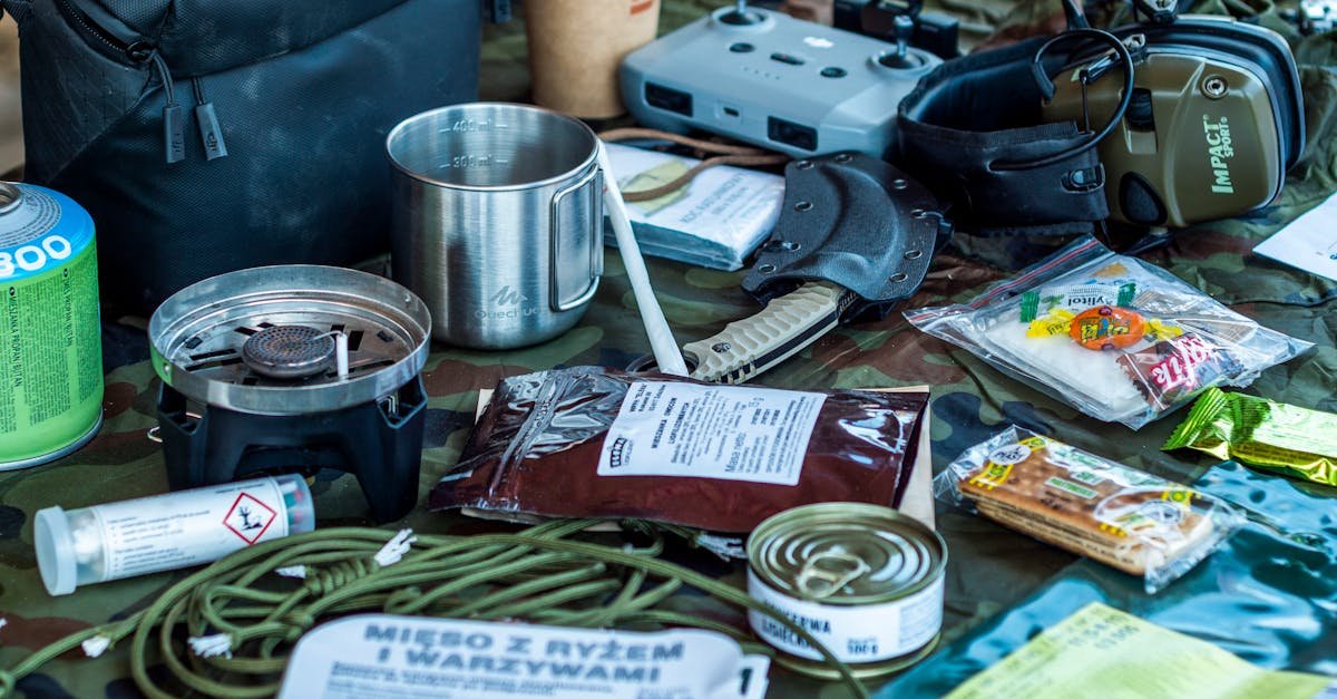 A diverse assortment of camping and survival items laid out, including food, tools, and gadgets.