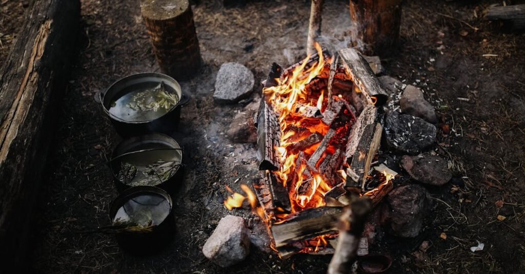 A cozy campfire with pots cooking in a rustic outdoor setting, perfect for wilderness adventures.